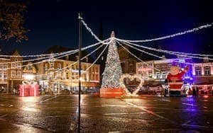 A festive night scene at Christmas market with lights and decorations.