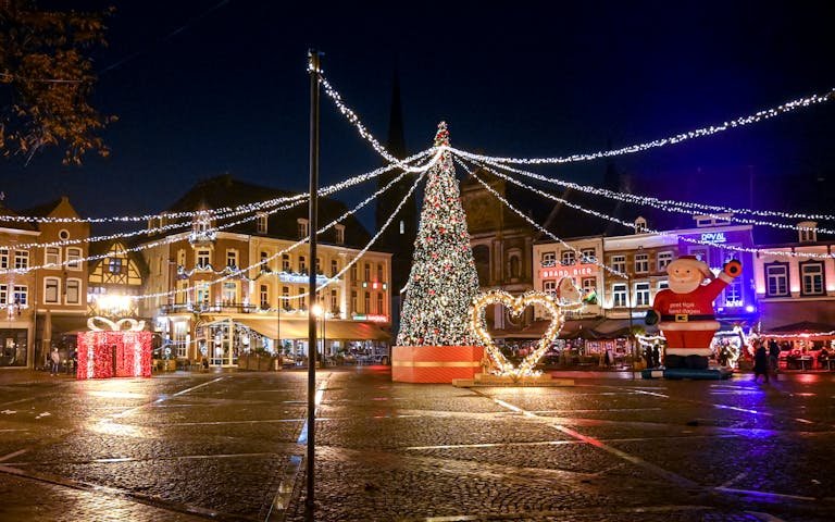 A festive night scene at Christmas market with lights and decorations.