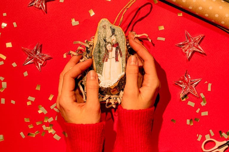 Festive scene with hands holding a snowman ornament, perfect for holiday décor.