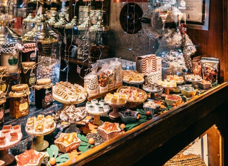 Showcase of assorted traditional sweets in candy shop decorated with string lights and balls for Christmas