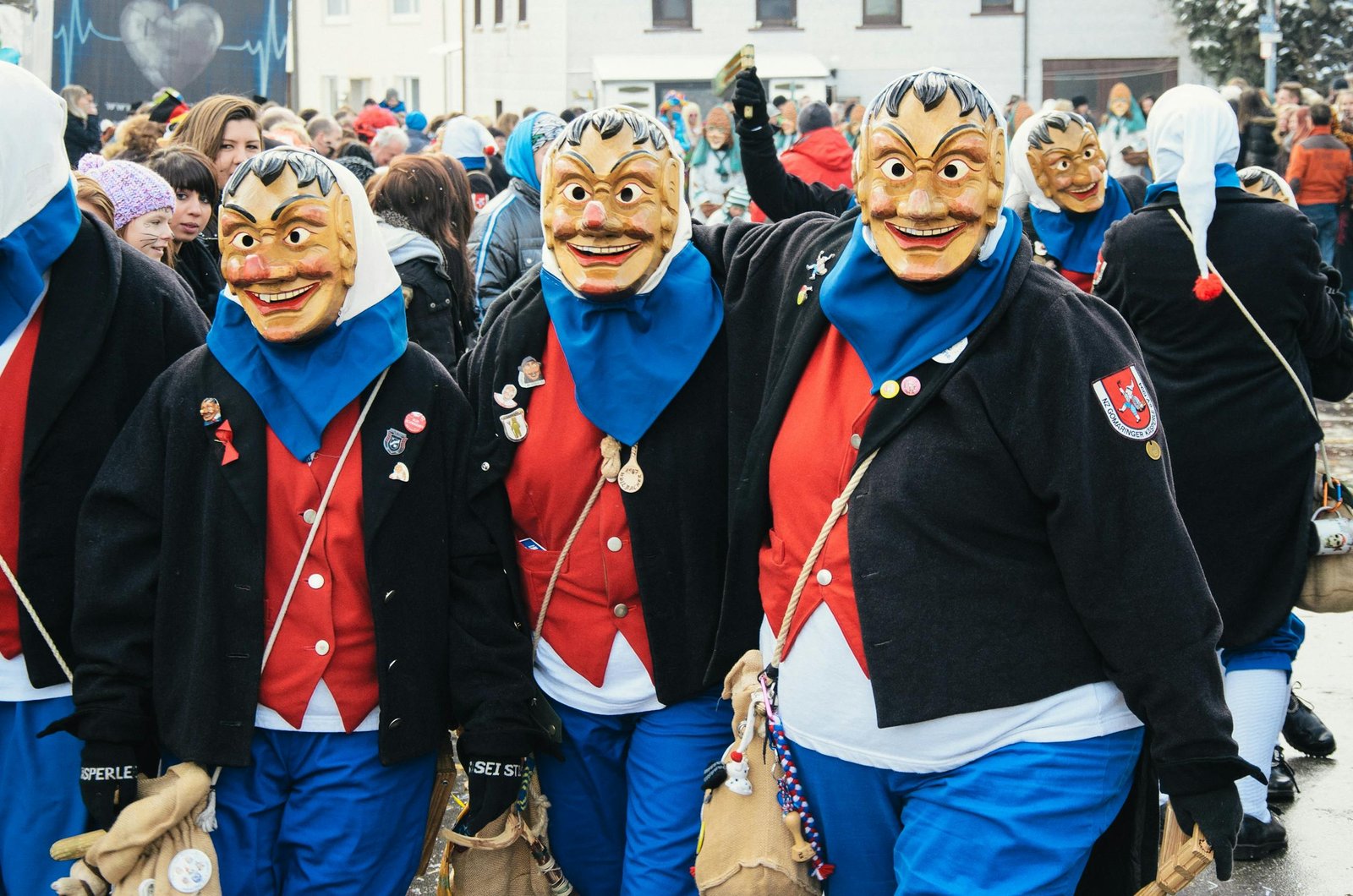 A lively street parade with masked participants in traditional costumes at a festival.