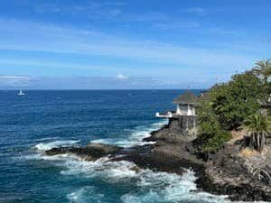 Beautiful coastline with waves crashing on rocks under a clear blue sky in Costa Adeje, Spain.