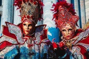 Intricate Venetian masquerade costumes with vibrant masks at a carnival in Venice.