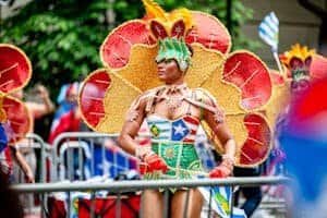Person in colorful costume participates in vibrant outdoor Carnaval parade, embodying festive spirit.
