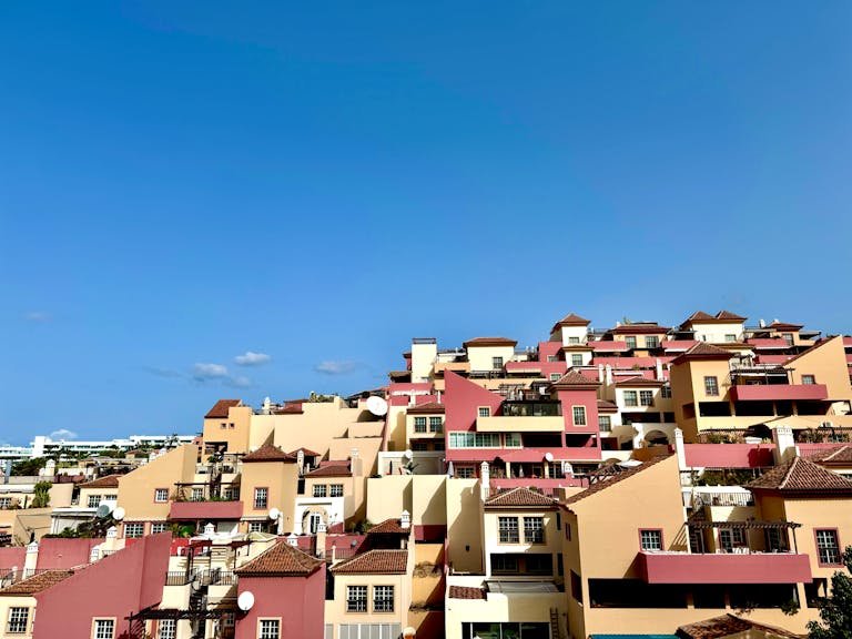 Colorful residential rooftops under clear blue sky in Costa Adeje, Spain, captured on a sunny day.