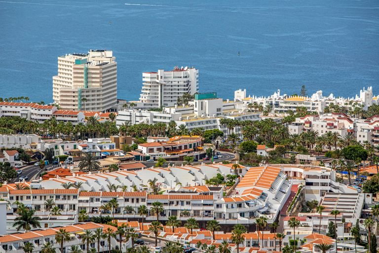 Aerial cityscape of Tenerife with coastal buildings and blue ocean view.