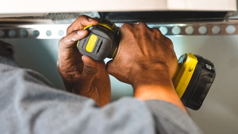 Close-up of worker's hands operating a power tool during a construction task.