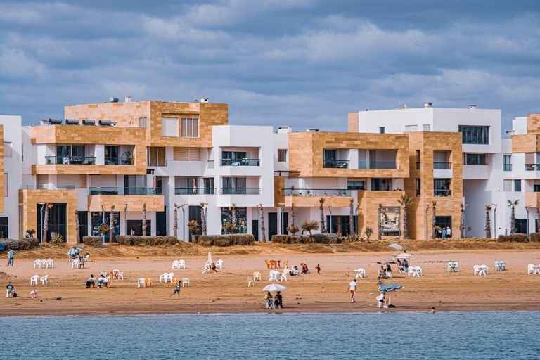 Coastal view of modern apartments and people enjoying a peaceful day at the beach.
