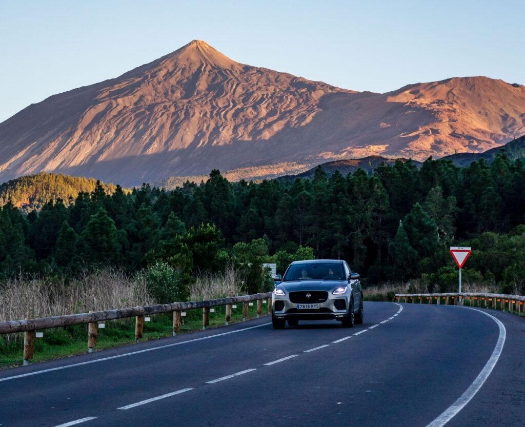 Car on a curvy road with Mount Teide in the background during daylight in Tenerife, Spain.